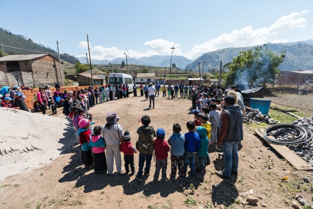 people standing forming circle near house under blue sky during daytime, Acercarse a las comunidades y comunicar de manera efectiva
