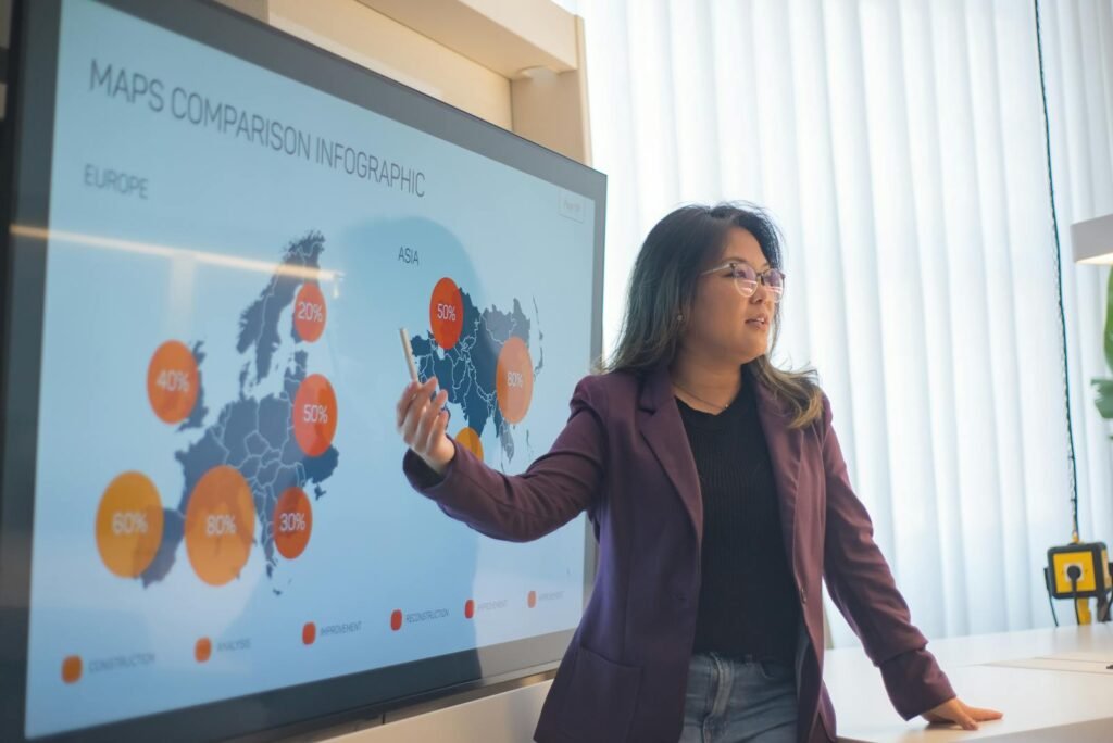 crear infografías profesionales, Asian woman presenting a business infographic on global market trends in an office setting.