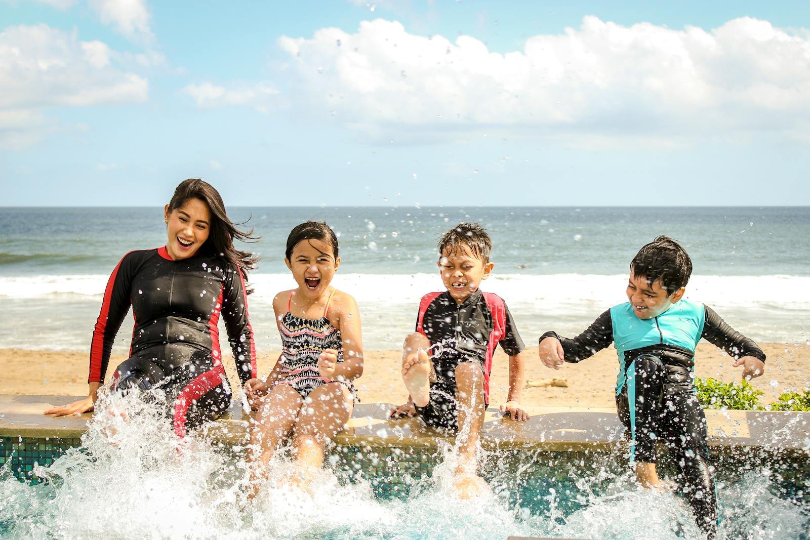 químicos de la felicidad, A family having fun splashing water near the seashore on a sunny day in Bali, Indonesia.