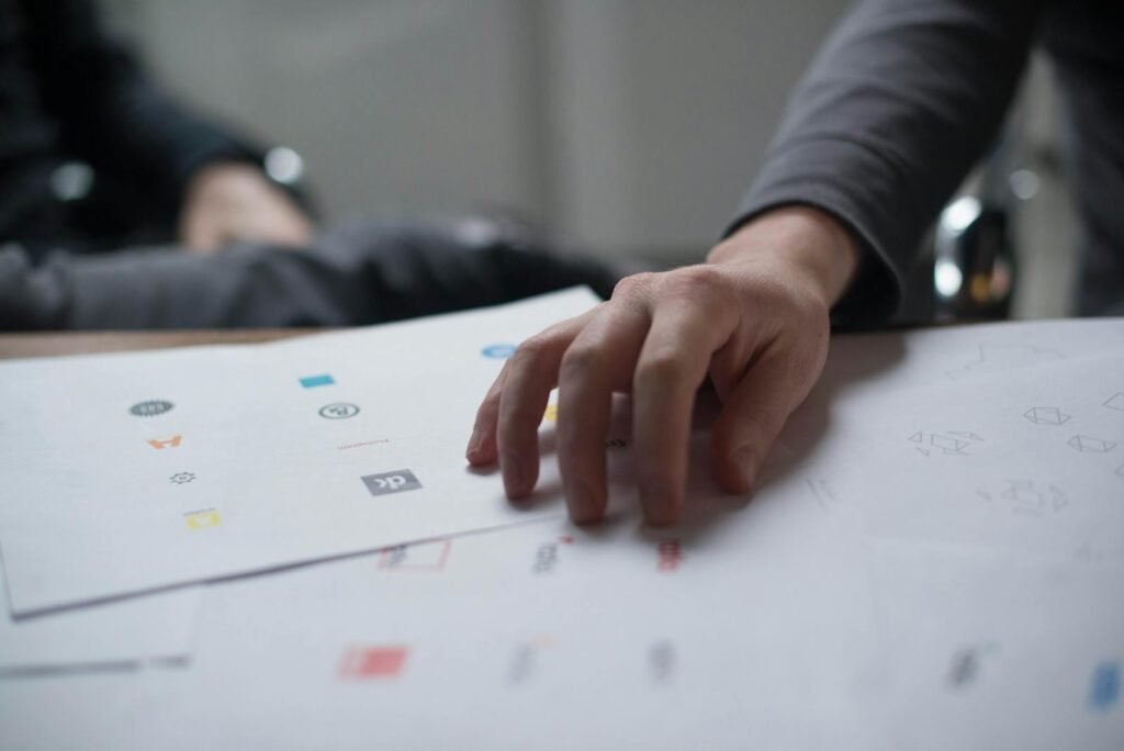branding y marketing, A close-up shot of a hand reviewing various logo designs on paper, ideal for business concepts.