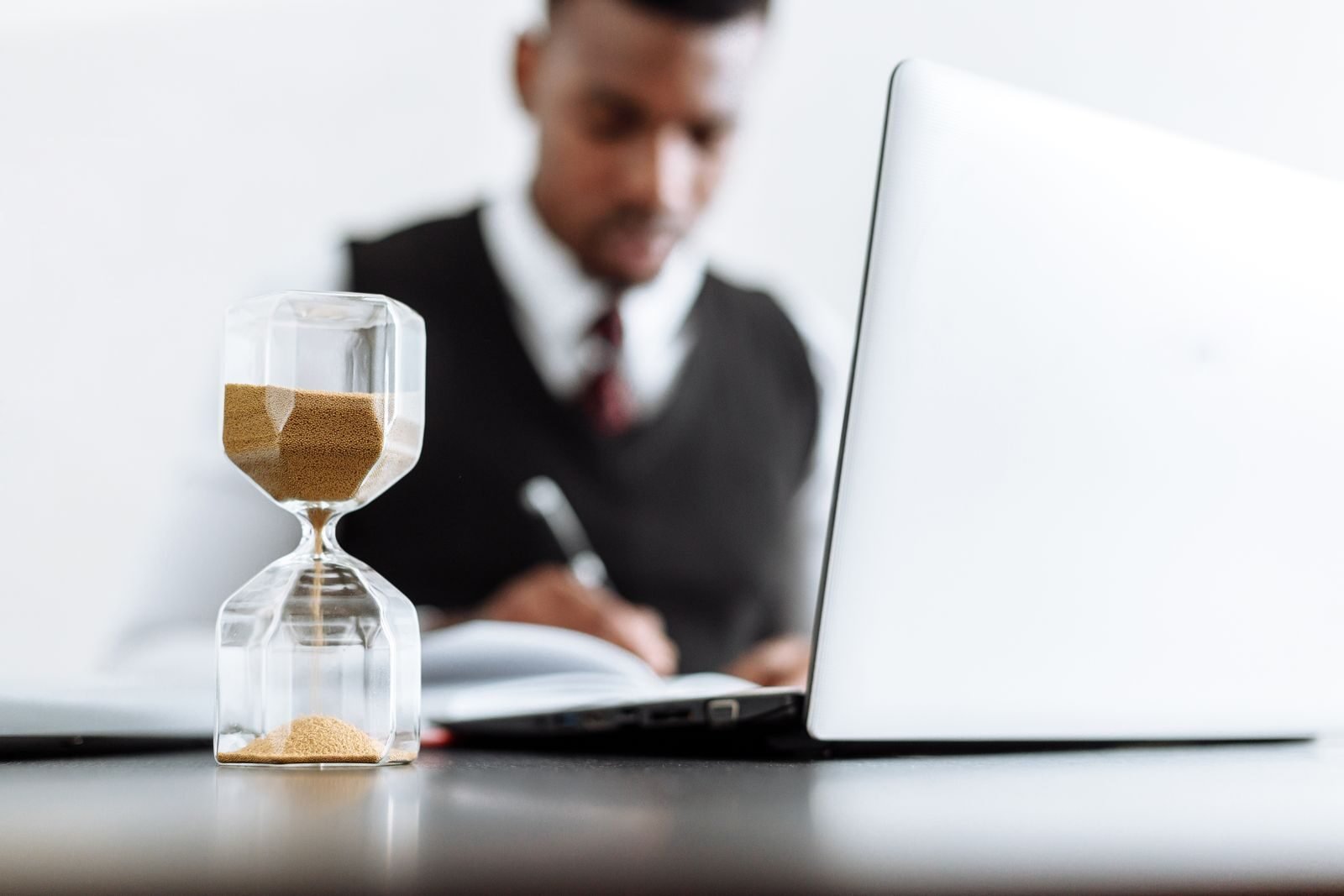 regla 80/20, Businessman at desk with hourglass indicating time management and daily work routine.