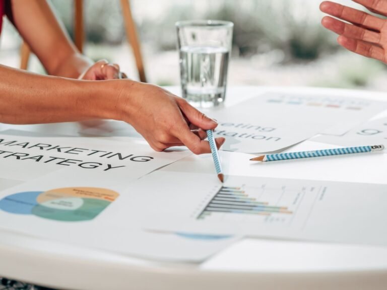 inbound marketing, Hands discussing marketing strategy with charts in an office setting.