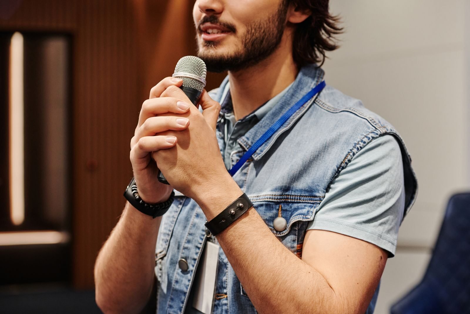 hablar en público, Man with a beard speaks into a microphone during an indoor seminar or presentation.