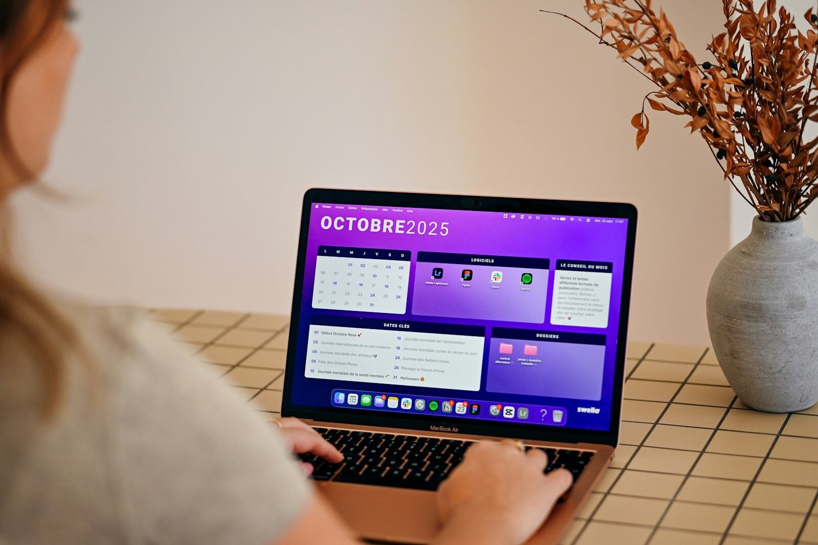 automatización de redes sociales, Woman using laptop with october 2025 calendar displayed.