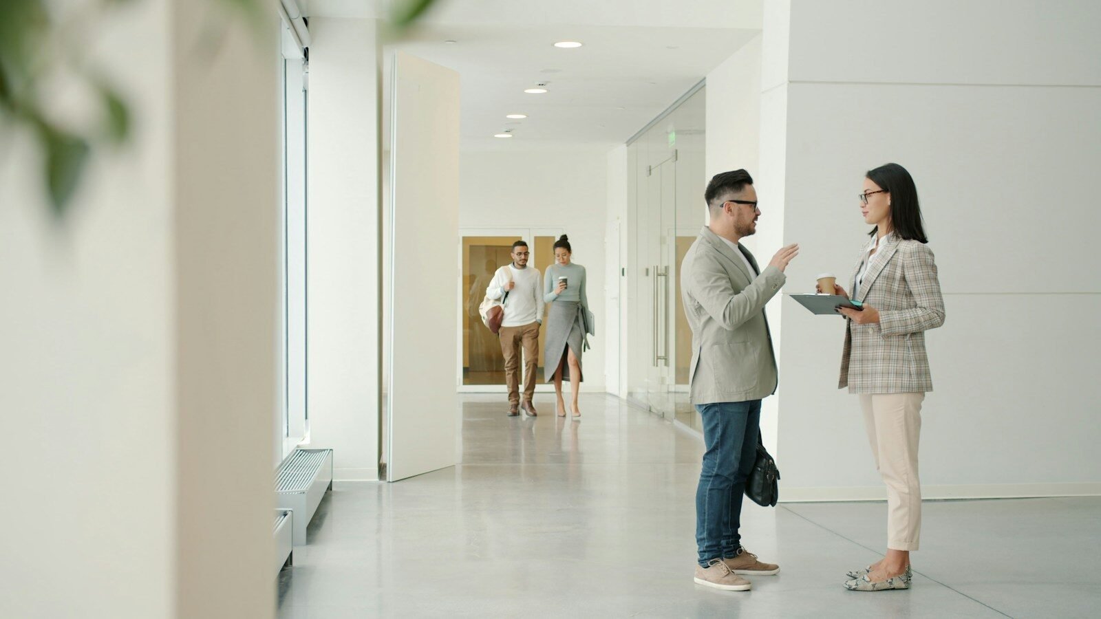 feedback constructivo, Two people talking in a modern office hallway