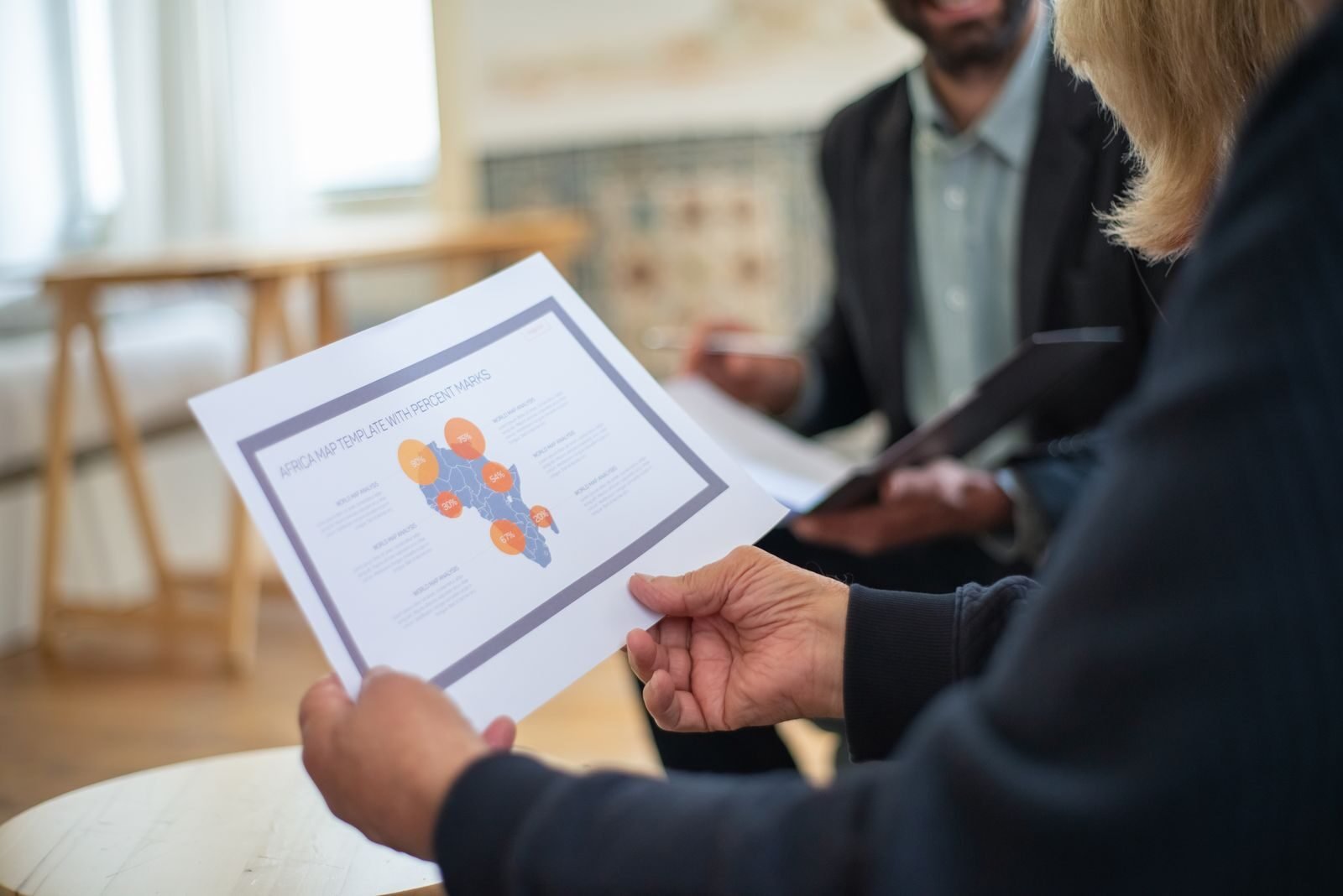 mapa de públicos, Three professionals discussing a data presentation in an office setting.